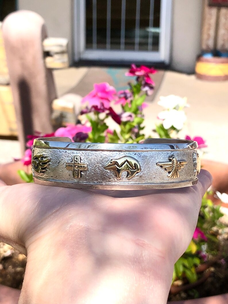 A person holding onto a silver bracelet with gold designs