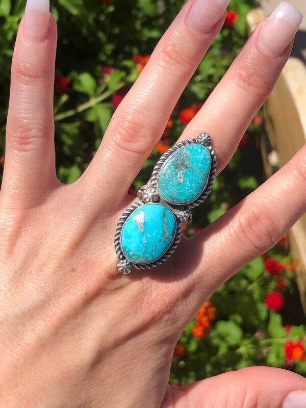 A person is holding their hand out to show the turquoise stone.