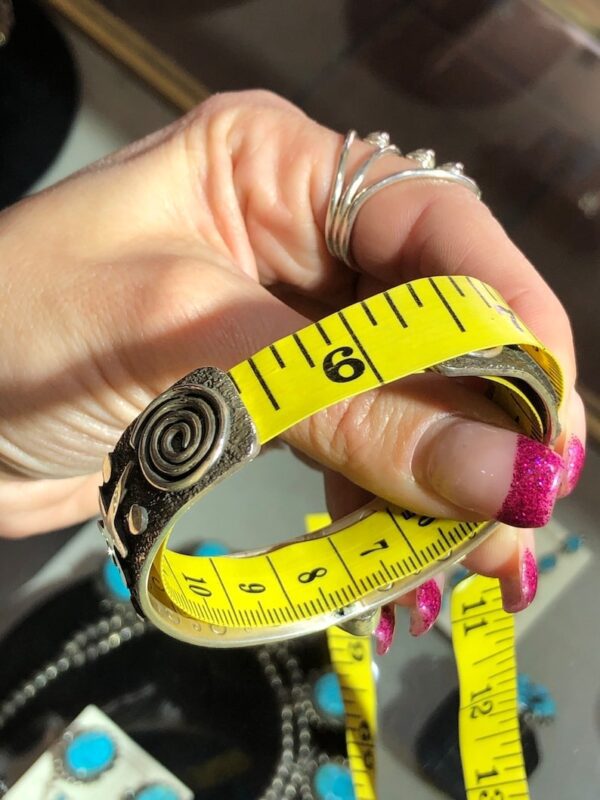A woman holding a yellow measuring tape bracelet.