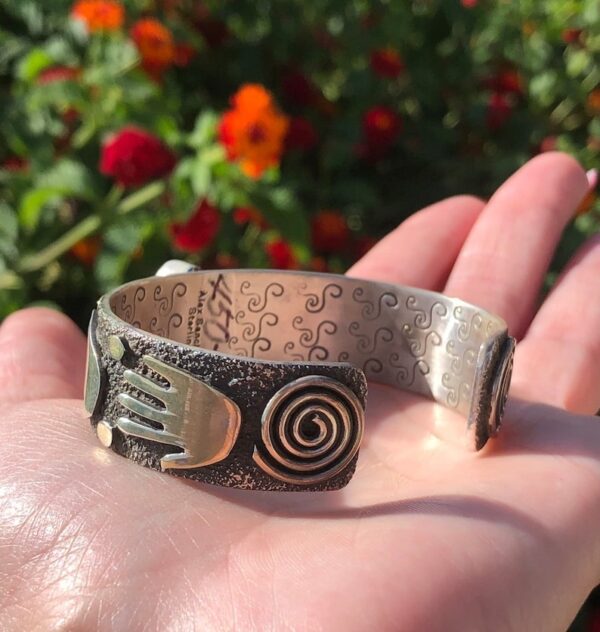 A hand and spiral bracelet in someone 's hand.