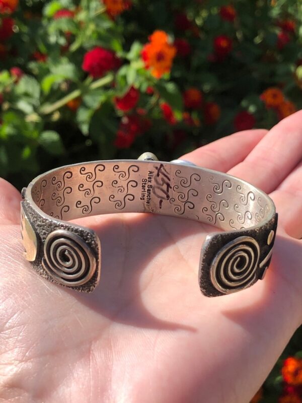 A person holding onto a silver bracelet with spirals