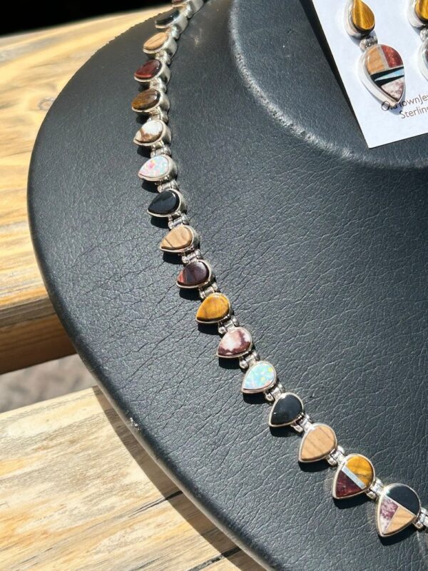 A black table with a necklace of different colored stones.