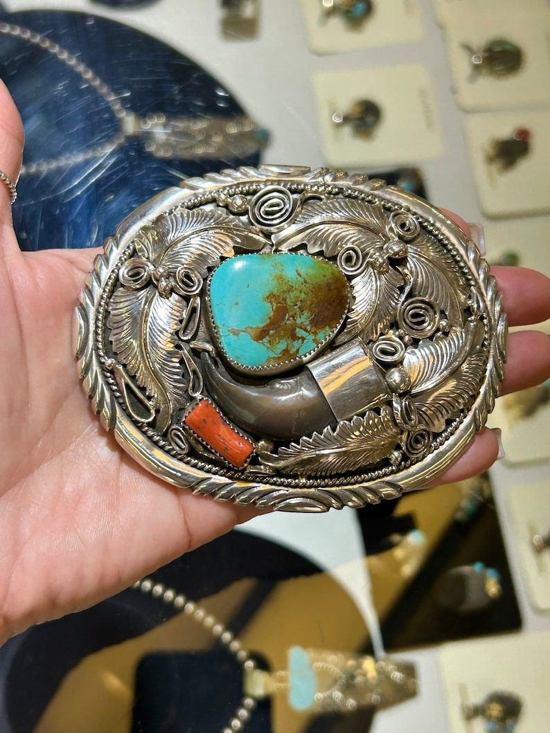 A person holding onto a belt buckle with turquoise