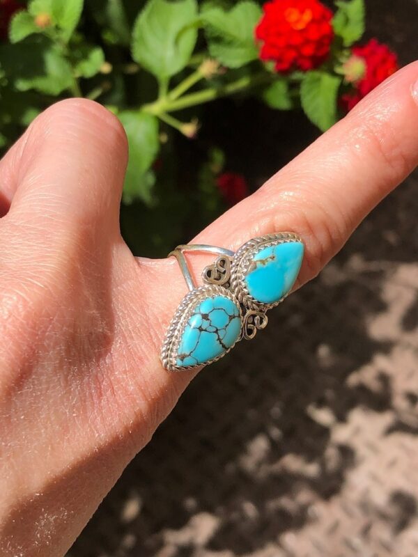 A person holding onto two turquoise rings