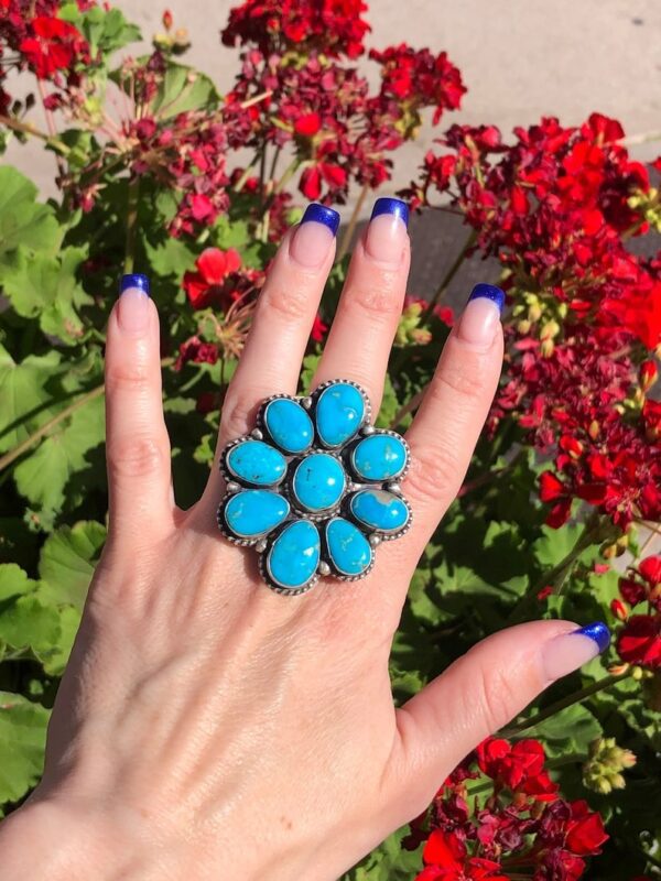 A woman is holding her hand up to the flower shaped ring.