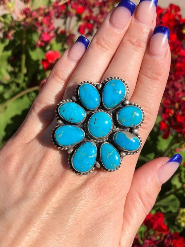 A woman is holding her hand up to the top of a flower shaped ring.