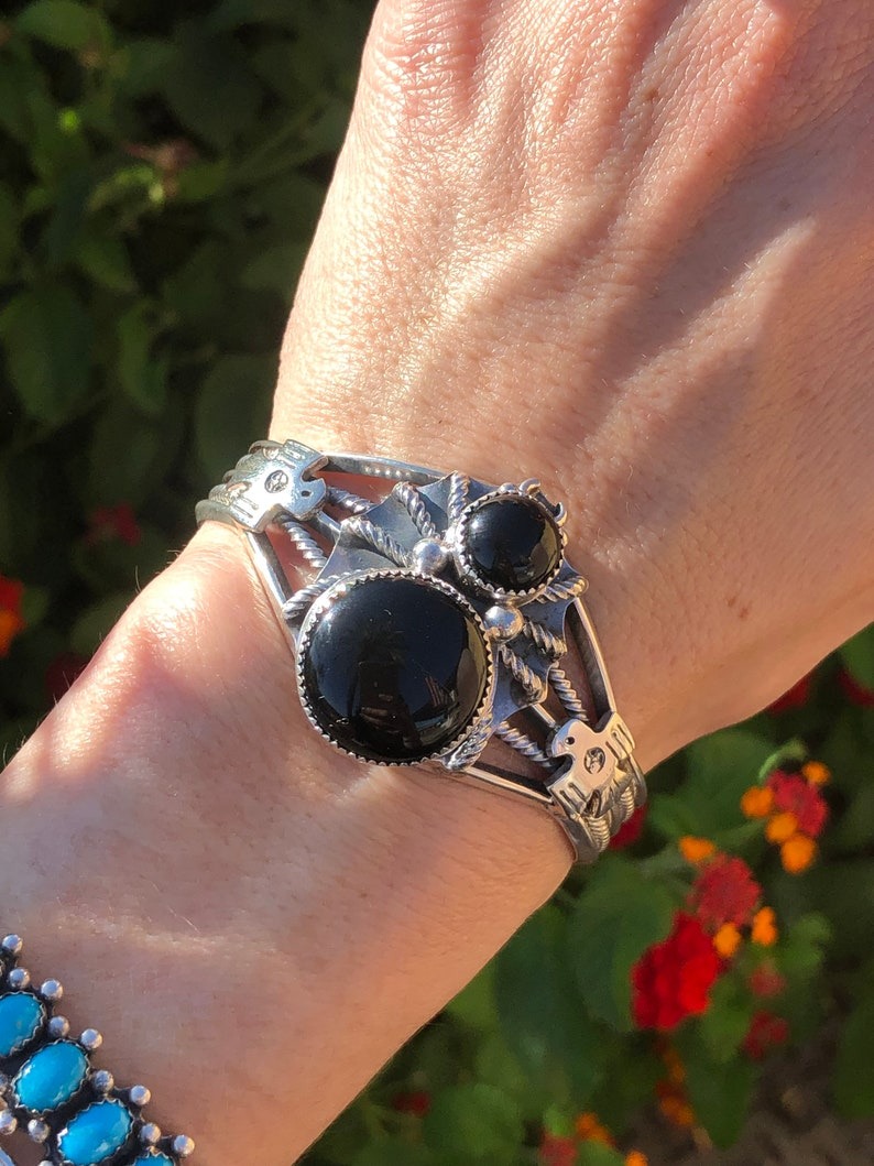 A woman wearing a bracelet with two black stones.