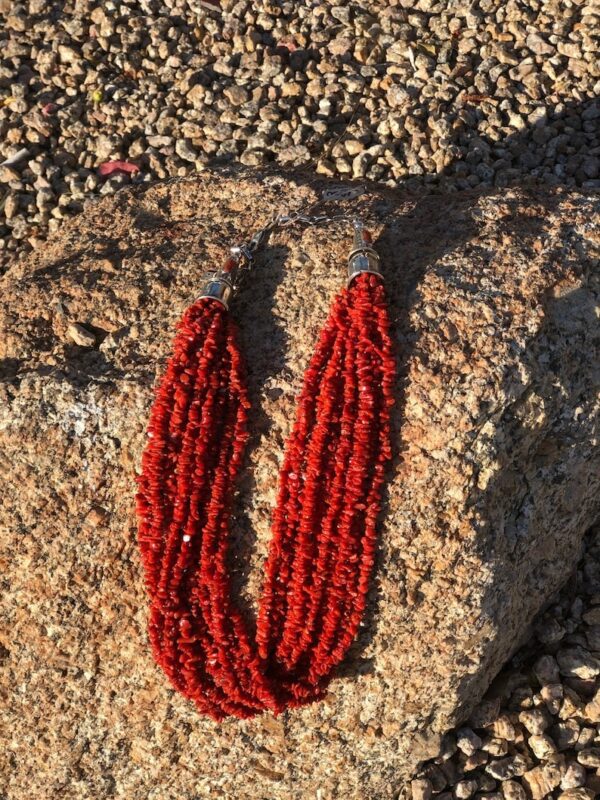 A red necklace is on the ground near some rocks.