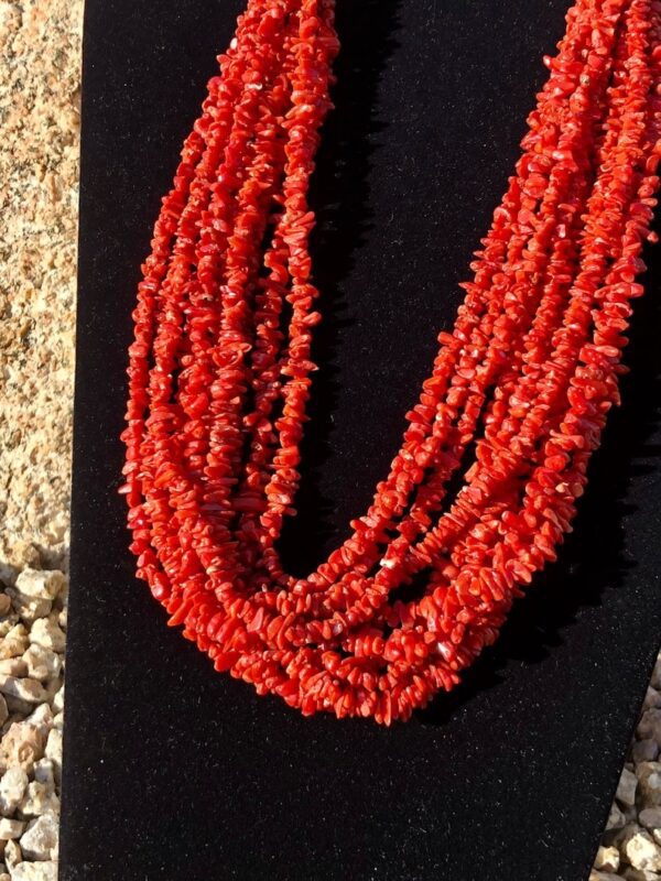 A display of red coral beads on black stand.