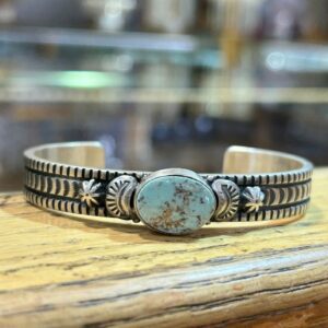 A silver bracelet with a turquoise stone on it.