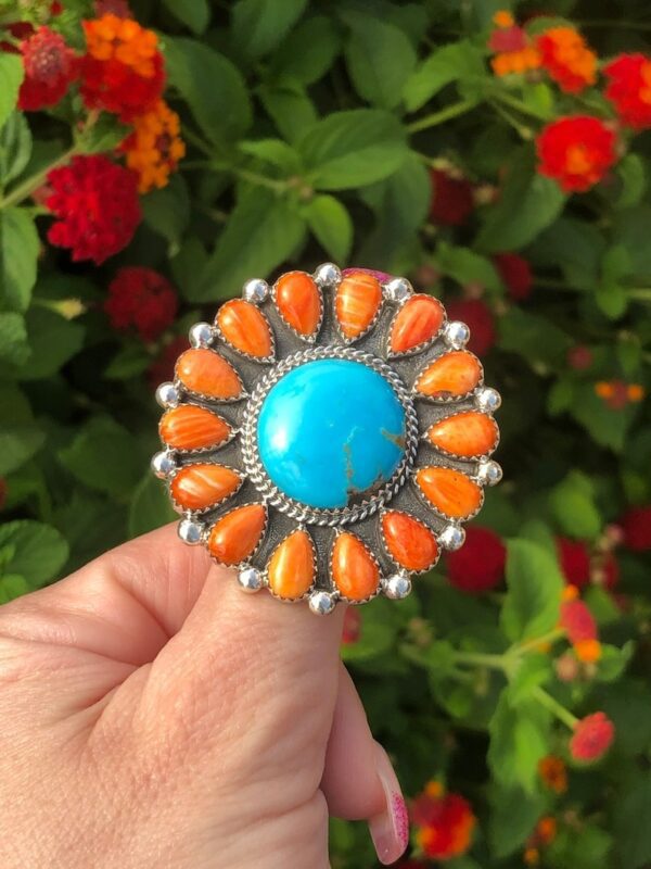 A person holding onto a ring with orange and blue stones