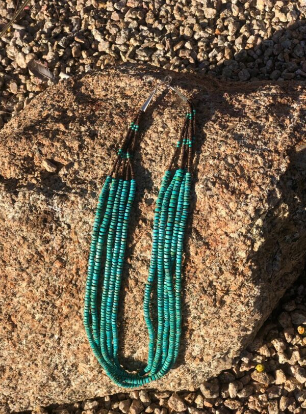 A pair of long green earrings sitting on top of a rock.