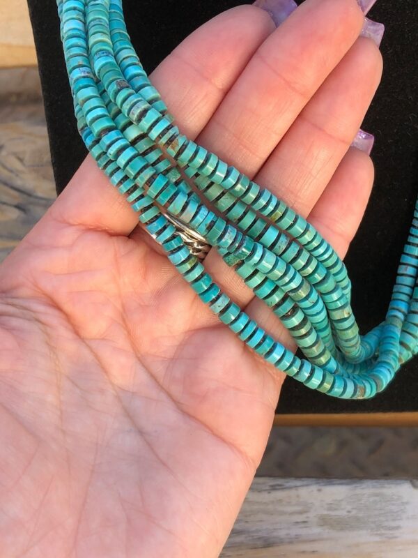 A person holding onto a string of turquoise beads