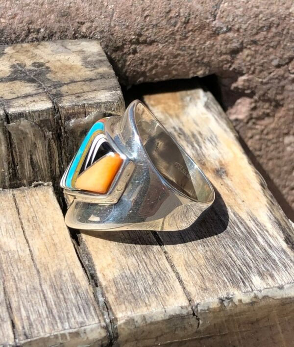 A silver ring with an orange and blue stone on top of it.