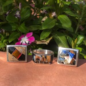 Three square rings sitting on a table next to flowers.