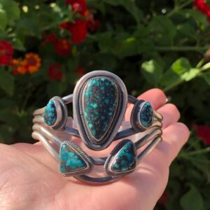 A person holding onto some turquoise jewelry