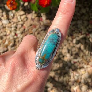 A person holding onto a turquoise ring