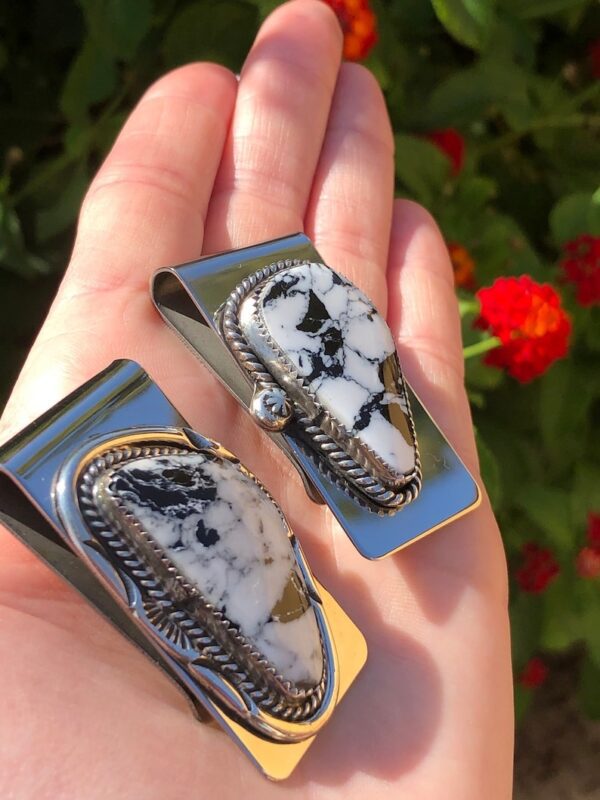 A person holding two different sized money clips.