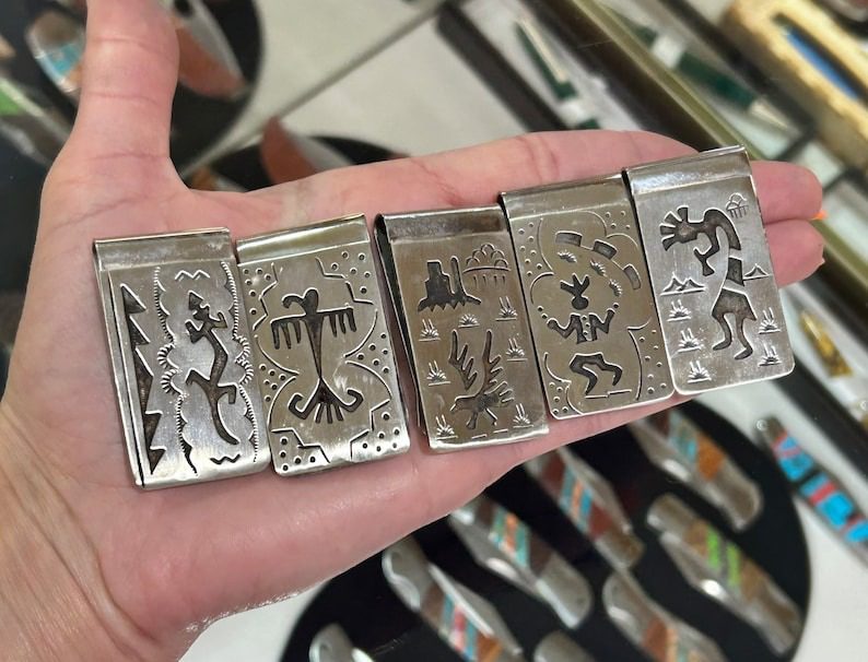 A hand holding five different metal cigarette cases.