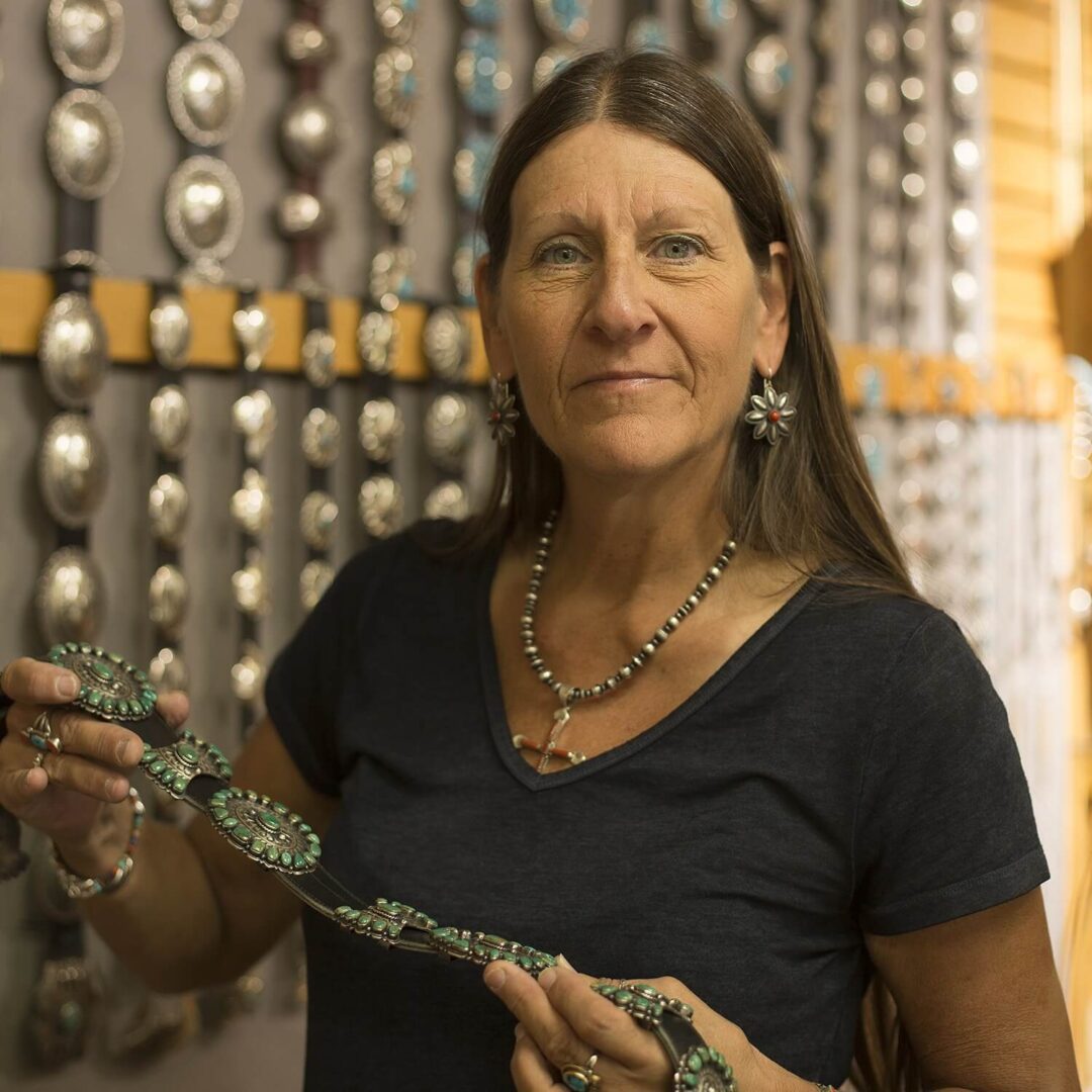 A woman holding a spoon in front of many other spoons.