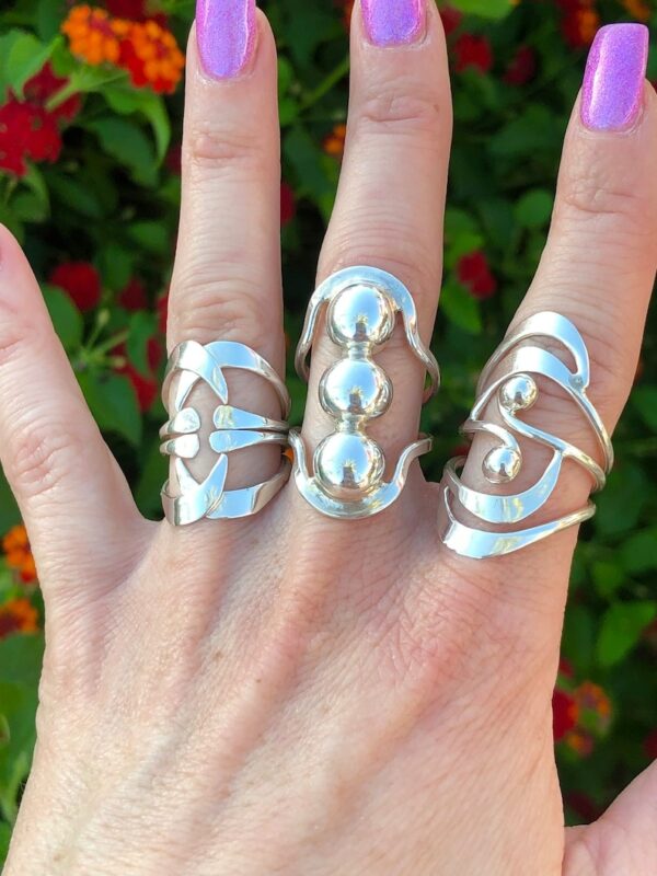 Three different rings are shown on a woman 's hand.