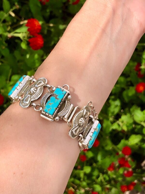 A woman 's hand wearing a bracelet with turquoise and silver.