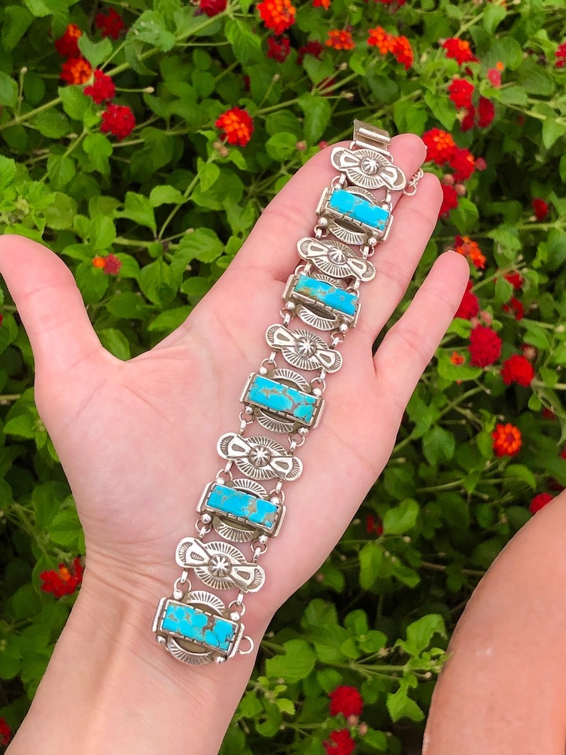 A hand is holding onto the turquoise bracelet.