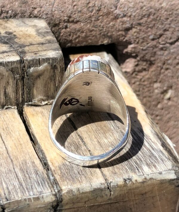 A silver ring sitting on top of a wooden block.