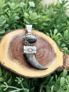 A wooden slice with a black stone and a tooth pendant.