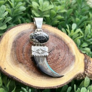 A wooden slice with a black stone and a tooth pendant.