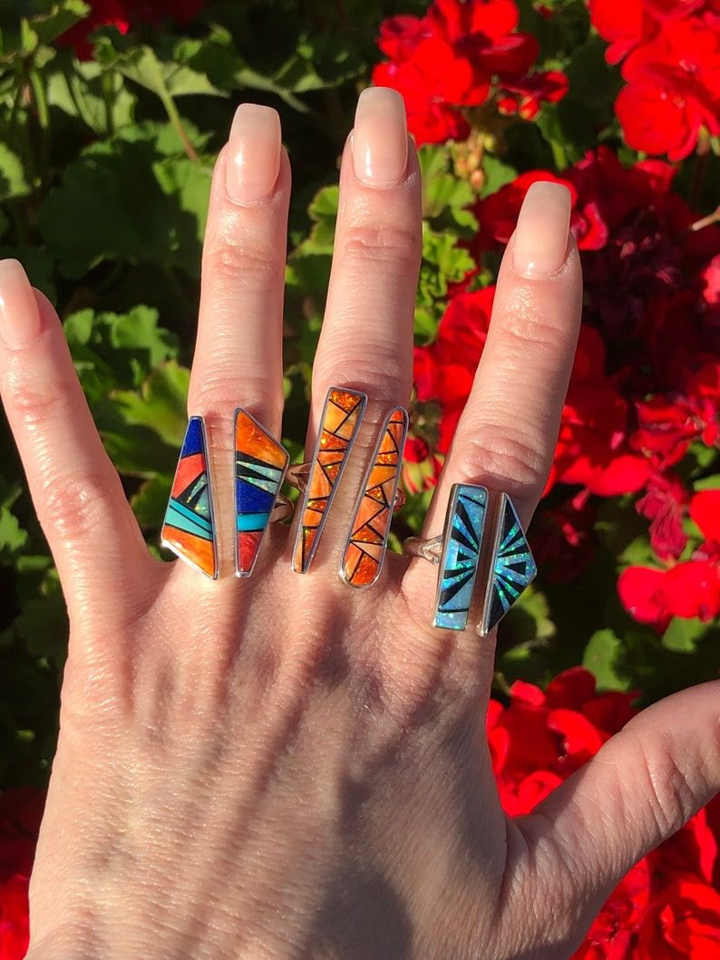 A hand with several different colored rings on it.