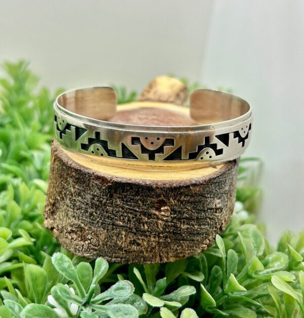 An Augustine Mowa Jr. Hopi Symbols Sterling Silver Cuff Bracelet with a pattern on it.