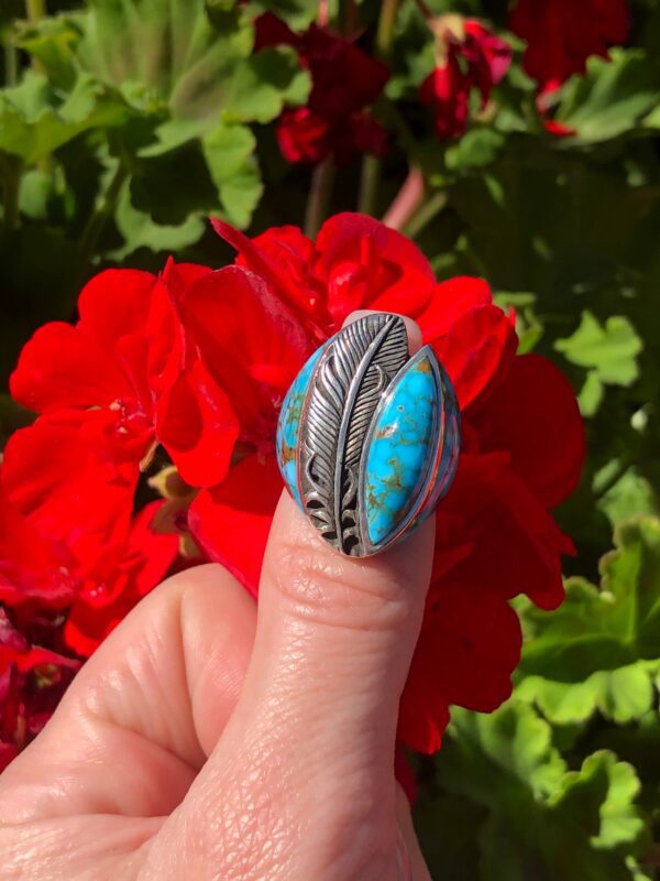 A turquoise and silver ring with a feather design.