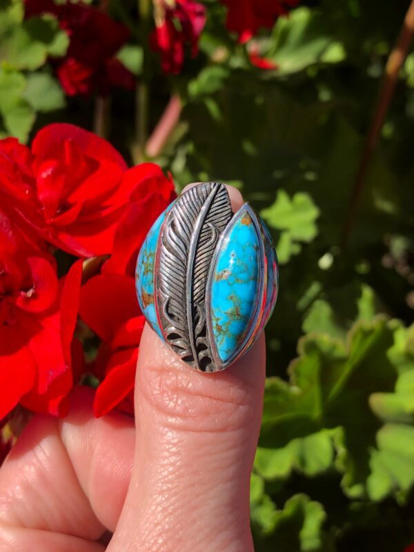 A silver ring with a blue stone and feather design.