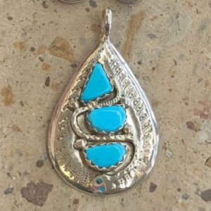 A silver pendant with turquoise stones and a pair of earrings.