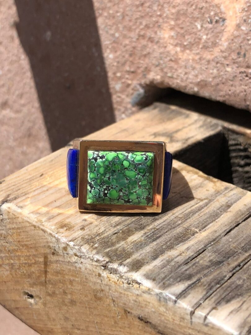 A green stone ring on top of a wooden bench.
