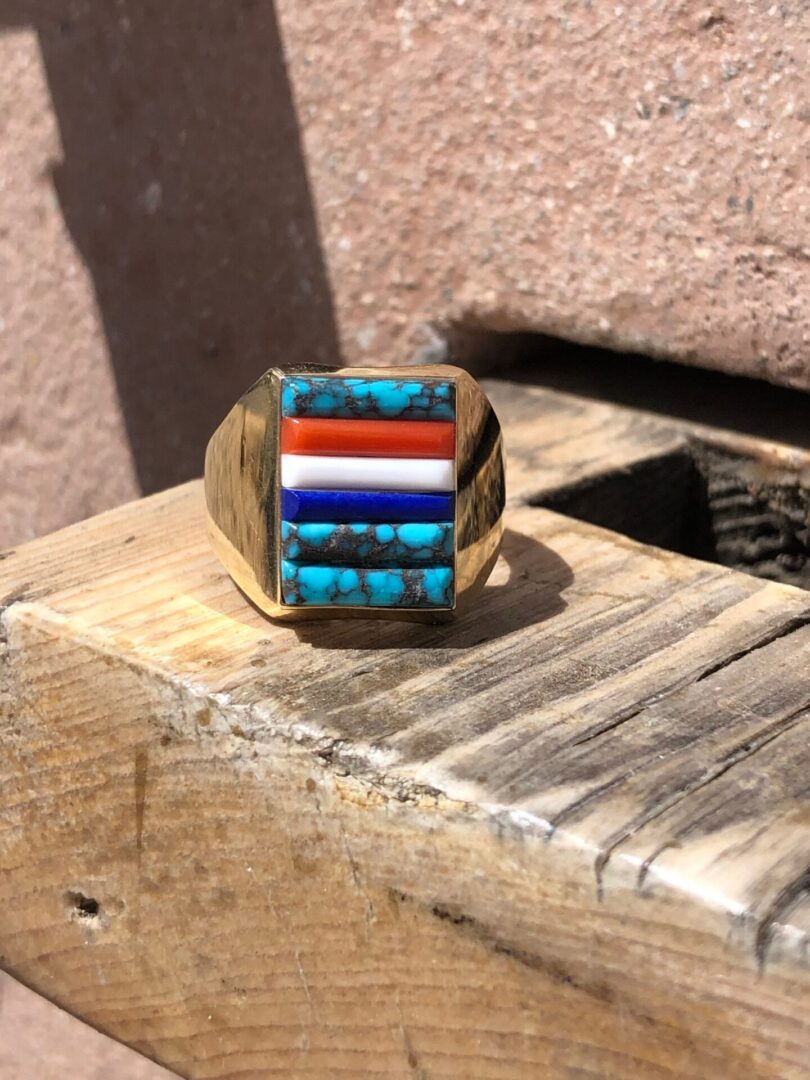 A gold ring with turquoise and orange stones.