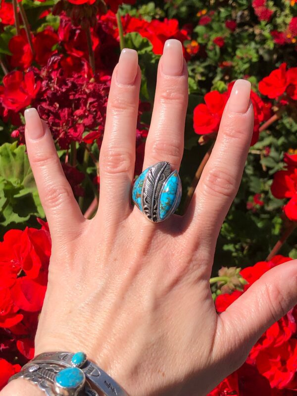 Hand wearing a silver ring with a blue stone.