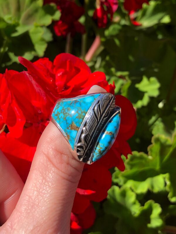 A silver ring with a blue turquoise stone and feather design.