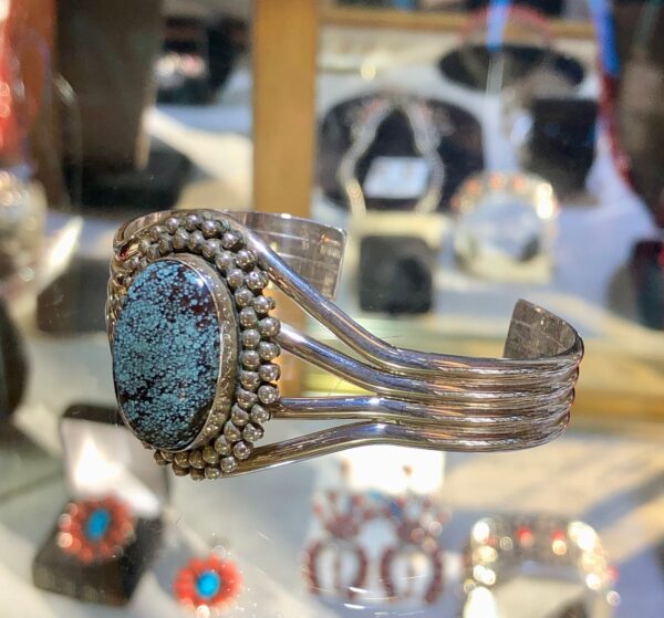 A silver bracelet with a large oval turquoise stone.