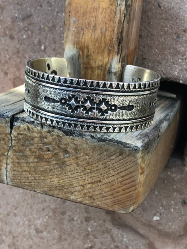 A silver cuff bracelet with a stamped design.