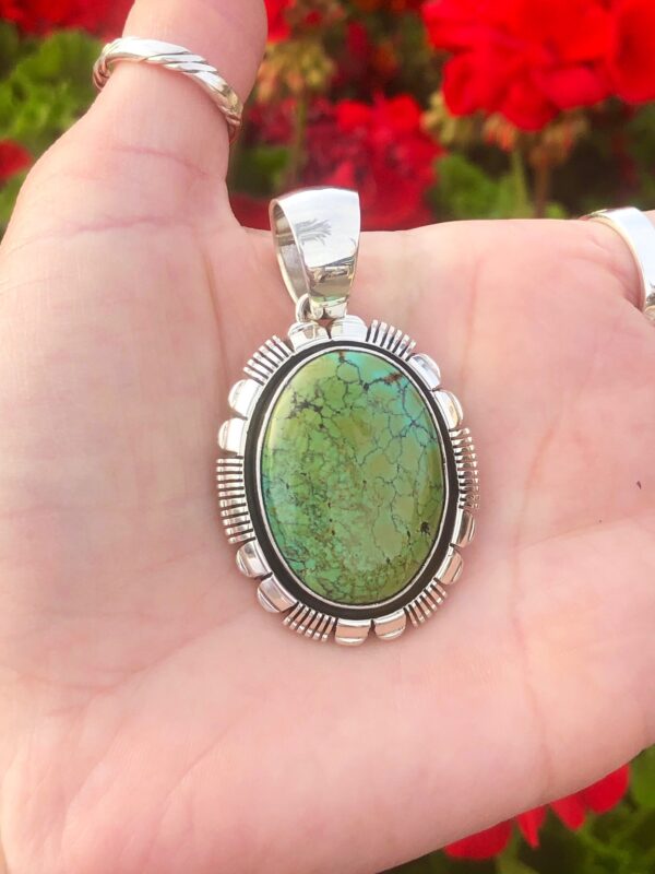 An oval green turquoise pendant with silver setting.