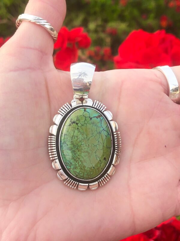 An oval green turquoise pendant with a silver frame.