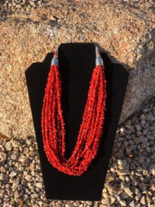 A red coral beaded necklace on a mannequin.
