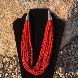 A red coral beaded necklace on a mannequin.
