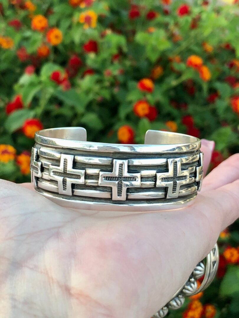A person is holding a silver cuff bracelet.