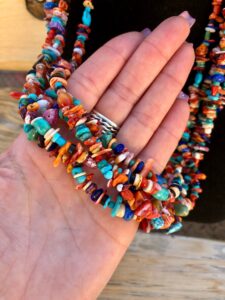 A person holding a colorful beaded necklace.