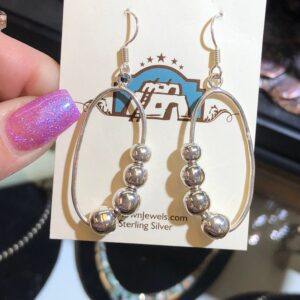 A person is holding a pair of silver earrings.
