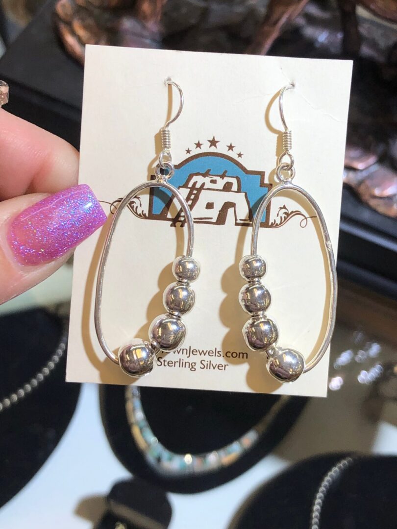 A person is holding a pair of silver earrings.