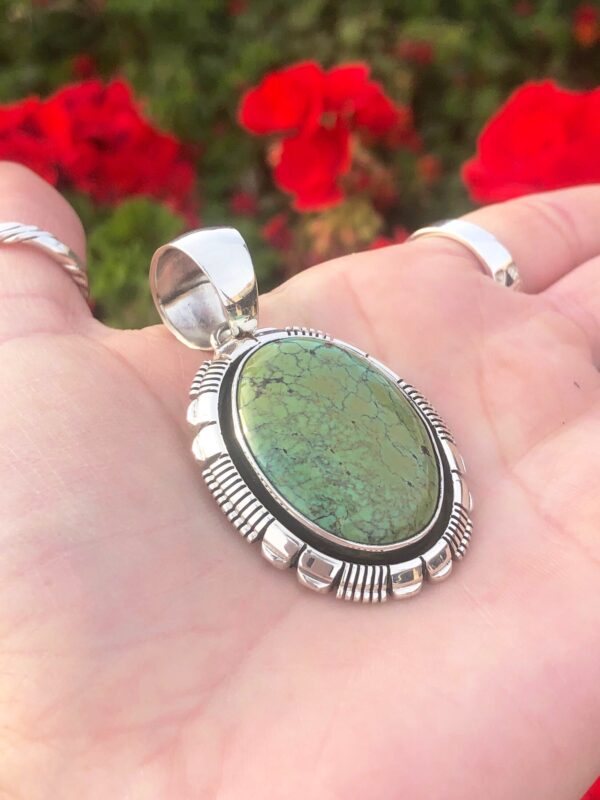 An oval green turquoise pendant in a silver setting.